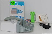 Complete set showing pet training collar with remote, litter scoop, green bone-shaped chew toy, and multi-colored rope toy.