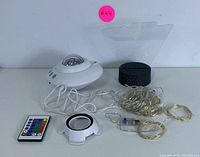 White LED projector, black holographic base, two USB string lights, and remote on white background