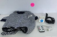 Full view of black and white striped pet jacket, training collar, and automatic cat teaser ball in box.
