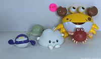 All five floating bath toys arranged around the large yellow crab dispenser showing their size and colors