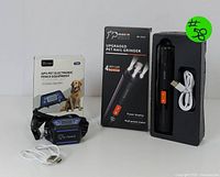Black rechargeable pet nail grinder with orange power switch, USB charging cable, and box labeled 'Upgraded Pet Nail Grinder' with LED lights and power display.
