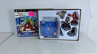 Photo showing the Disney Infinity 2.0 Marvel Super Heroes Starter Pack box for PS3 including game disc, base, and four collectible figures (Iron Man, Thor, Black Widow, and another character).