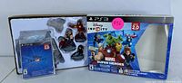 Disney Infinity 2.0 Marvel Super Heroes Starter Pack box open showing the game base, game disc sealed in case, and three Marvel figurines: Iron Man, Thor and Black Widow.