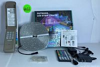 Photo of the set including the rolled LED strip light, its packaging, a remote control, wiring components, and the garage door keypad.