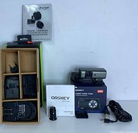 Complete set spread including the dash cam, user manual, charger with battery adapters, USB cable, car charger, and original box.