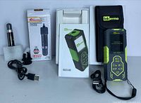 InkErma laser distance meter in box with carrying case and USB cable, alongside boxed Xianglong USB aquarium heater with cable and mounting clip.