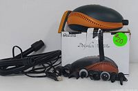Black and orange electric air pump with attached hose and multiple nozzles resting on box with label showing product name and green pricing sticker.
