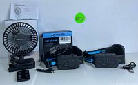 Two rechargeable headlamps with packaging box, USB cables, and a small black desk fan with clip base and remote control, arranged against white background.