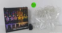 Box for star curtain lights showing multi-colored stars with power adapter in foreground.