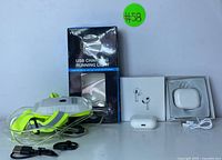 Complete lot showing the wireless earbuds in a white charging case, the boxed USB charging running light, and accessories including USB cable and clips.