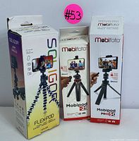 Three boxed tripods showing manufacturer names and model details