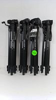 Four black Soligor T175 tripods standing upright side-by-side showing folded legs, brand markings visible.