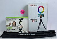Photo of boxed Digipower Go Viral vlogging kit and Mobifoto Mobilite O6R ring light tripod kit with Cameron M100 tripod case in front.
