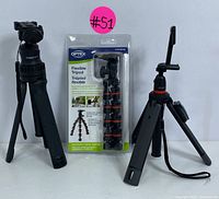 Three tripods on display: Mobifoto tripod on left, packaged Optex flexible tripod in center, Joby compact tripod on right with smartphone mount and wrist strap.