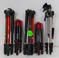 Five tripods arranged upright showing the colors, styles, and sizes of four Joby tripods and one Manfrotto tripod.