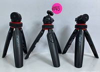 Three Mobifoto branded tripods, standing unfolded showing adjustable legs and ball head mounts with red accent rings.