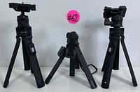 Front view of two Joby tripods and one Mobifoto tripod with legs extended, showing the tripods and mounts.