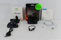 Full lot overview showing all items: iQ Pod TWS earbuds in open and closed charging case, hearing amplifier in black charging case, magnetic wireless charger with connected white USB charging cable, and additional short USB cable.