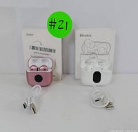 Two sets of wireless earbuds with charging cases and USB cables, one pink set branded Jxrev and one white set branded Btootos, displayed in front of their boxes.