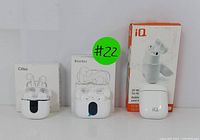 Three wireless Bluetooth earbuds with charging cases and original packaging, including brands Cillso, Btoots, and iQ with wireless charging capability.