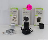 Three Digipower Power Wall Chargers (white 12W, black 24W dual USB, black 12W) with matching USB to Lightning charging cables (silver braided and black rubberized) displayed standing upright next to their packaging.