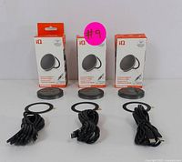 Four boxed magnetic wireless chargers displayed on a white surface with their charging pads, adhesive rings, and USB-C cables laid out in front of them.