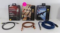 Three HDMI cables with packaging: Monster M2000 brown braided 1.5m, Monster M3000 blue braided 3m, and black Energy Performance II 1m cable.