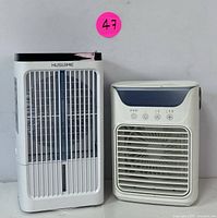 Front view of Husuime tower fan (left) and compact cooling fan (right) placed side by side on a white surface