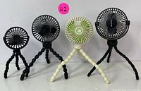 Four flexible tripod USB rechargeable fans, three black and one white, standing side by side showing size and design variation