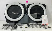 Two Mobifoto LED ring lights with carrying cases and accessories laid out, showing included mounting parts and power adapters.