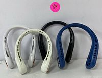 Four portable neck fans in white, black, and blue colors shown front-facing and side by side against white background.