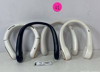 Four portable neck fans (two white, two navy) arranged side by side with a white USB charging cable in front.