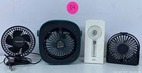 Four USB rechargeable fans arranged side by side on a white background. From left to right: black clip-on fan with cord, black square desk fan, turquoise handheld fan, and a silver handheld fan in box.