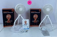 Two boxed versatile handheld stroller fans with white flexible tripods, USB cables, mesh bags and warranty cards shown on white background.