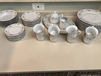 Overview photo showing all pieces including plates, cups, serving platter, creamer, and sugar bowl arranged on countertop