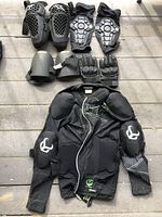 Full lot overview showing jacket, protective pads, and gloves laid out on floor.