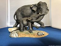 Photo of gray porcelain elephant figurine featuring an adult and calf with textured skin and painted base