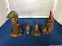 Front view of 4 garden gnome resin figurines in various stances and sizes, signed by Tom Clark.