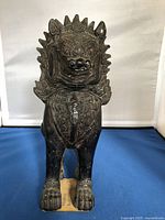 Front view of the intricately carved traditional Asian wooden sculpture featuring detailed patterns and fierce facial expression.