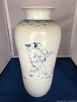 Full view of the tall white porcelain vase decorated with blue sumo wrestler figures and a blue scroll pattern around the neck.