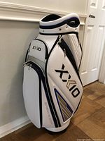 Front and side views of white XXIO golf carry bag showing logos, pockets, and overall shape.