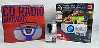 Boxed Proscan CD Radio Boombox with red and blue color, RCA Home Theater Projector Bundle box, and boxed Bluetooth Smartwatch displayed on a white background.