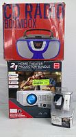 Photo of the boxed Proscan CD Radio Boombox and RCA Home Theater Projector Bundle with smart watch packaging visible, showing the product names and features on the packaging.