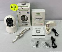 AI Smart Camera with box, charging cable, and other components on display.