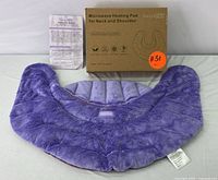 Photo of the microwave heating pad showing the plush furry side in bright purple, alongside the original product box and printed instructions.