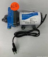 Front view of DC House water pressure pump wrapped in plastic with attached power cord and plug.