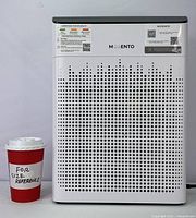 Front view of Morento air purifier with perforated intake design and size comparison cup labeled 'For Size Reference'.