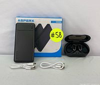 Asperx power bank with its original packaging, wireless earbuds in charging case and two USB cables displayed on a white surface.