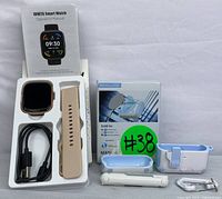 IDW26 Smart Watch in box with beige wrist strap, charging cable, and operation manual alongside the portable UV sterilizer box and handheld cleaning brush.