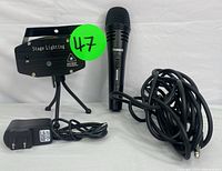 Black stage laser light with tripod legs, power adapter, and Tonor wired dynamic microphone with cable on white background.